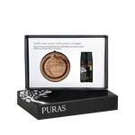 Puras essential oil gift set in a black presentation box, featuring a round wooden diffuser tray and a small dark glass essential oil bottle with a black cap, shown against a white background.