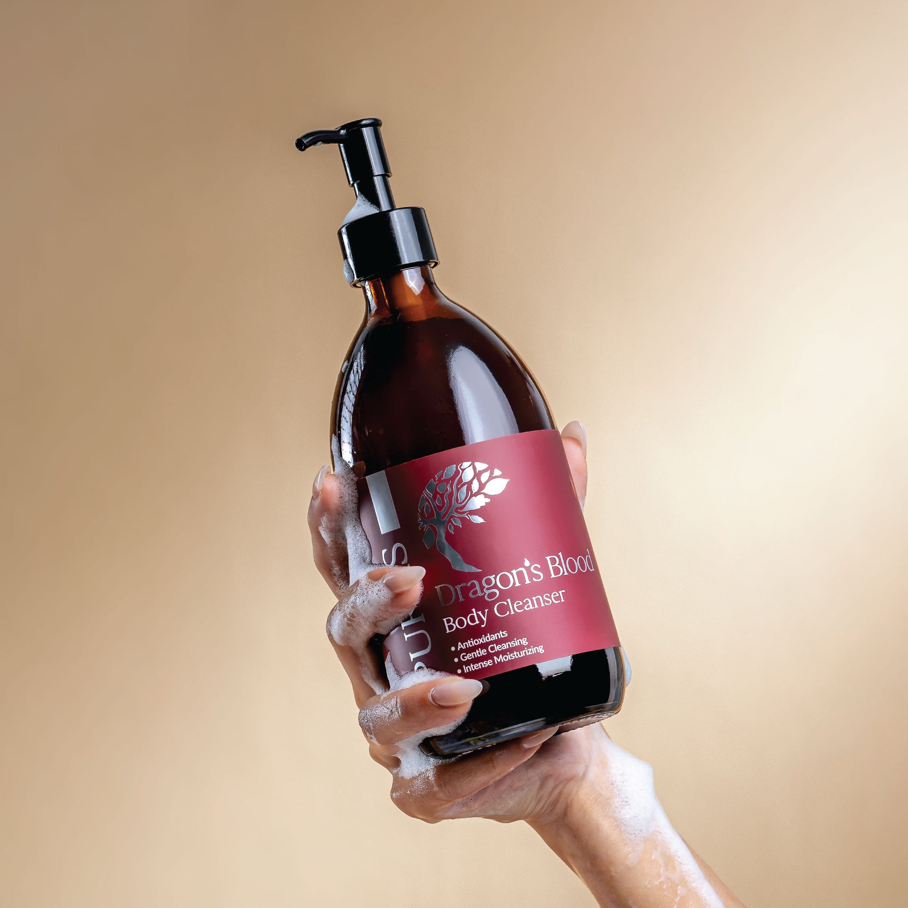 Hand holding a bottle of 'Dragon's Blood' body cleanser with a beige background