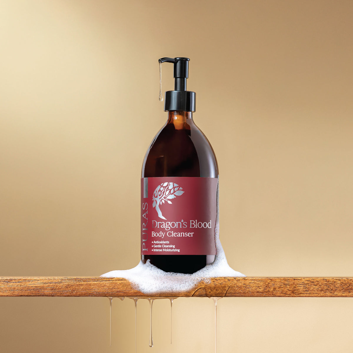 Bottle of 'Dragon's Blood' body cleanser with a pump with texture on a wooden surface against a beige background