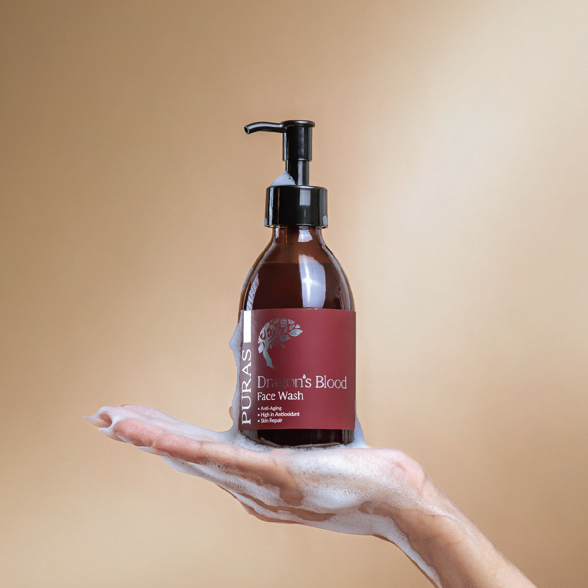 Bottle of Puras Dragon's Blood Face Wash with a hand holding foam on a beige background