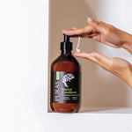 Hand holding a bottle of Puras Revival Conditioner with a pump.
