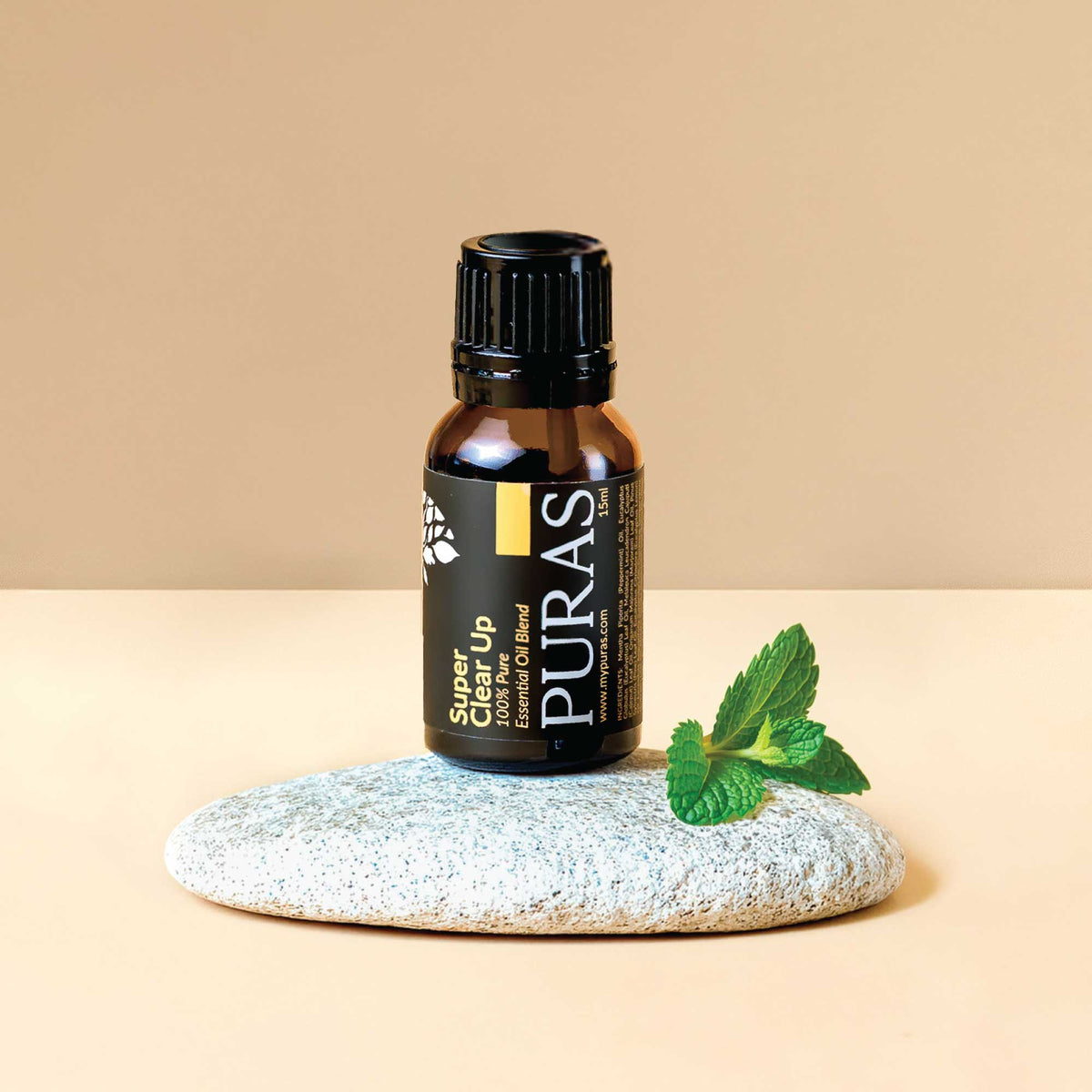 Puras "Super Clear Up" essential oil bottle on a stone with a leaf on a beige background